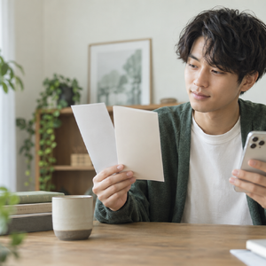 スマートフォンと資料を見ながら脱毛メニューを比較する男性