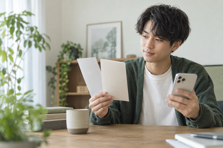 スマートフォンと資料を見ながら脱毛メニューを比較する男性